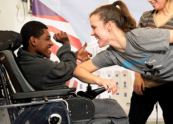 a boy in a wheelchair and a woman smiling at each other